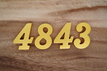 Golden Arabic numerals on a real brown and white wooden floor number 4843