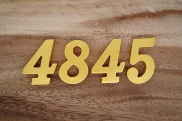 Golden Arabic numerals on a real brown and white wooden floor number 4845