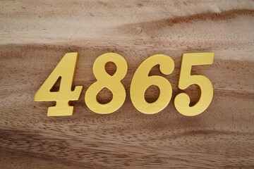 Golden Arabic numerals on a real brown and white wooden floor number 4865