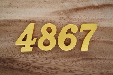 Golden Arabic numerals on a real brown and white wooden floor number 4867