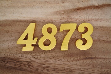 Golden Arabic numerals on a real brown and white wooden floor number 4873