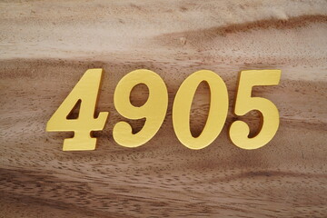 Golden Arabic numerals on a real brown and white wooden floor number 4905