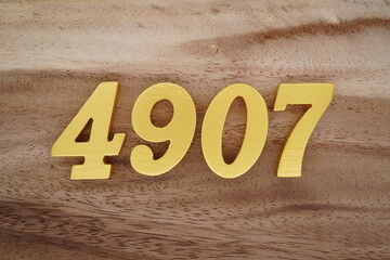 Golden Arabic numerals on a real brown and white wooden floor number 4907