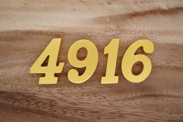 Golden Arabic numerals on a real brown and white wooden floor number 4916