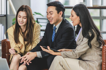 Group of millennial Asian young happy male female businessman businesswoman employee staff in formal business suit sitting on leather sofa smiling discussing brainstorming talking together in office
