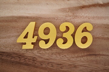 Golden Arabic numerals on a real brown and white wooden floor number 4936