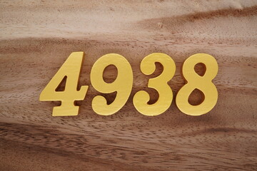 Golden Arabic numerals on a real brown and white wooden floor number 4938