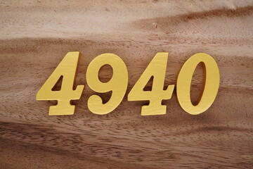 Golden Arabic numerals on a real brown and white wooden floor number 4940