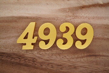 Golden Arabic numerals on a real brown and white wooden floor number 4939