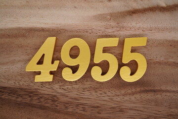 Golden Arabic numerals on a real brown and white wooden floor number 4955