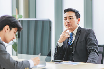 Closeup shot Asian happy professional successful male businessman employee in formal business suit sitting smiling holding fist up celebrating customer job goal agreement done achievement in office