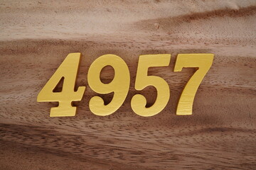 Golden Arabic numerals on a real brown and white wooden floor number 4957