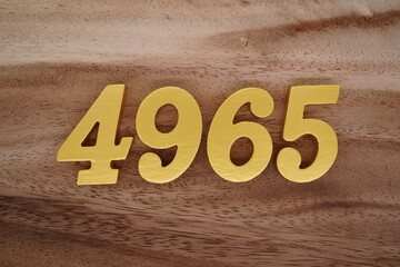 Golden Arabic numerals on a real brown and white wooden floor number 4965