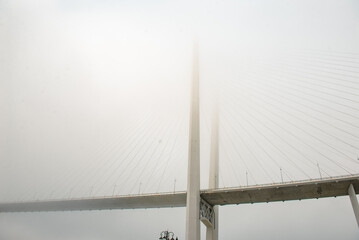 a beautiful bridge over the sea disappears in the fog. the bridge dissolves into the sky.