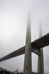 a beautiful bridge over the sea disappears in the fog. the bridge dissolves into the sky.