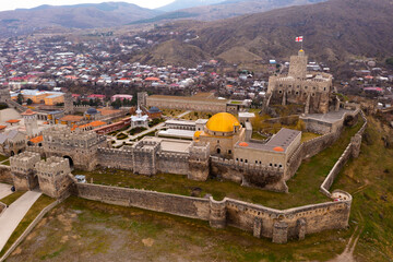 Scenic view from drone of walled ancient Akhaltsikhe Rabati Castle with golden domed Ahmediye Mosque on background with cityscape on spring day, Georgia