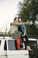 Stylish couple sitting on top of the retro bus and posing for a photo