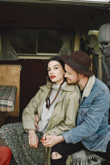 Cropped photo of stylish couple sitting indoors and posing for a photo