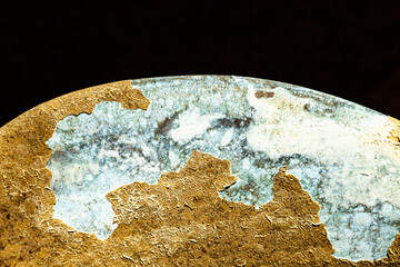 Part of an old bronze ship propeller with traces of corrosion and peeling paint, close-up. Abstract, scratched, bronzed texture.