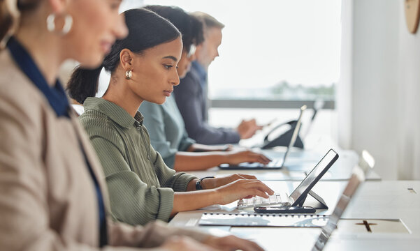 Logging inquiries as they come through. Shot of a young businesswoman working on a digital tablet alongside her colleagues in a call centre.