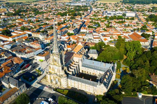 View from drone of houses and ancient Roman Catholic Cathedral of Lucon town at summer day, France