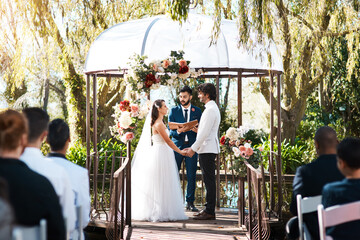 Stepping into holy matrimony. Cropped shot of a handsome young male marriage officiant joining a young couple in marriage outdoors.