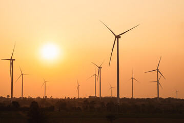 Windmills for electric power production, windmill farm or wind park with high wind turbines for generation electricity at sunset. Green energy concept.