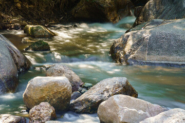 Naklejka na ściany i meble Water flowing along rocks in nature, waterfall
