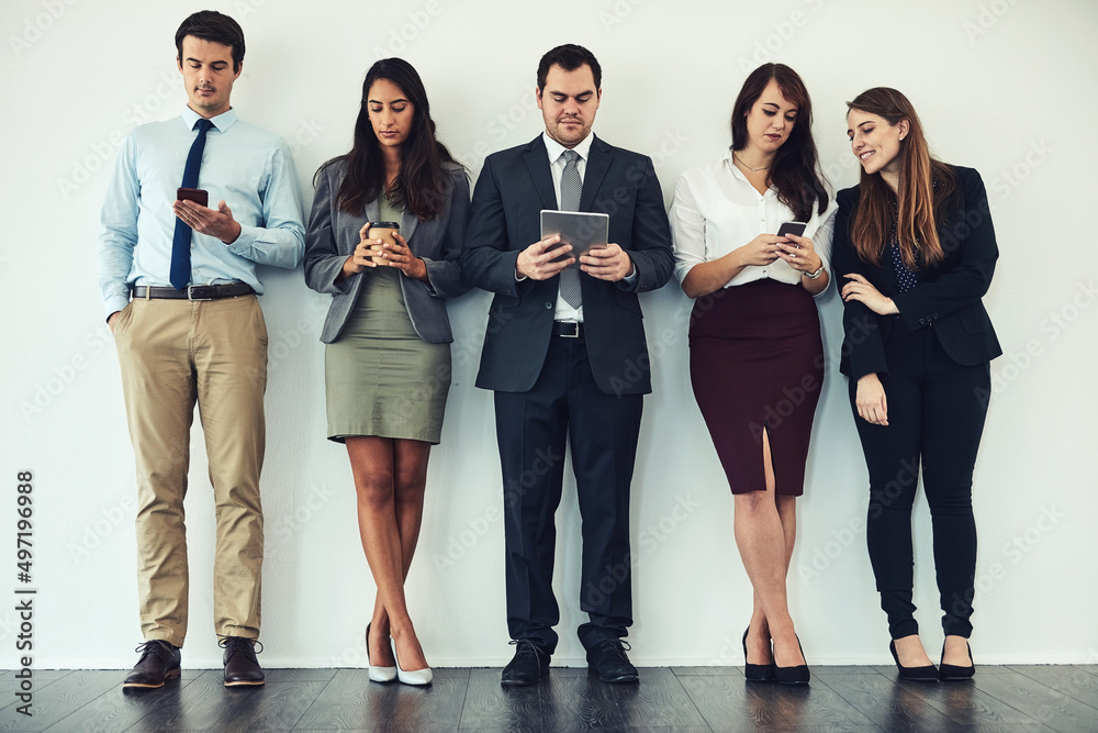 Poster Wireless entertainment while they wait. Studio shot of a group of businesspeople using wireless technology while standing in line.