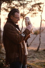 Man and wild bird over sunset sky in forest looking on each other Owl symbol of power, wisdom...
