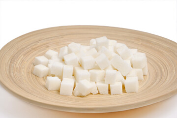 Refined sugar in a wooden plate on a white background.