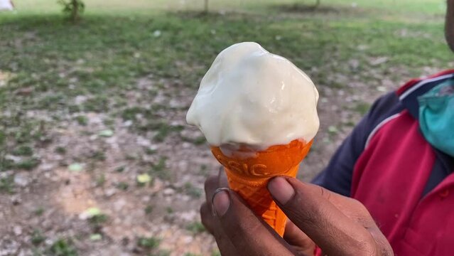A male staff in uniform careful preparing ice snowy softy from vanilla ice cream cart in outdoor.