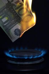 inflation in europe concept, 100 euro banknote burns on a gas burner on a kitchen stove