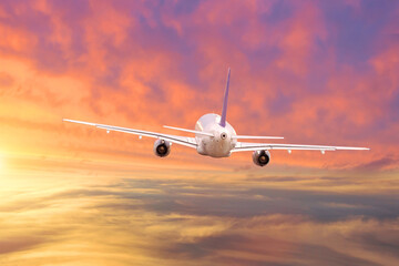 The plane flies into the distance the sunset sky is beautifully brightly lit.