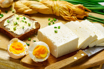 tasty lunch in rural style, healthy food - bread and butter sandwich, feta cheese, eggs, green leek and rye bread, cooked food on a white wooden boards