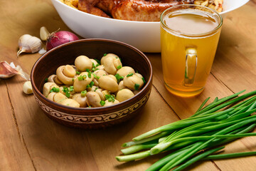 fried chicken meat and roasted potatoes on a white platter, a glass of beer, champignon mushrooms and green onions, delicious food on a wooden background
