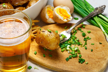 tasty lunch in rural style, healthy food - glass of beer, fried chicken meat and potatoes, garlic and green onions, cheese, boiled eggs and salt, cooked food
