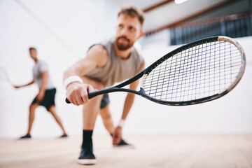 dont take your eyes off the ball for one second. Shot of two young men playing a game of squash.