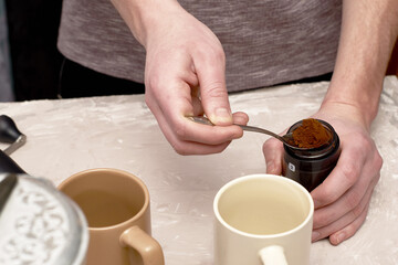 a person prepares coffee in a geyser, pours ground coffee into a geyser strainer