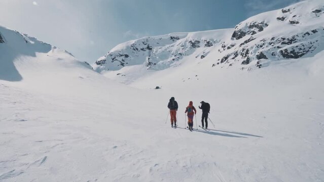Friends hiking up snowy Norway mountain for skiing trip, handheld view