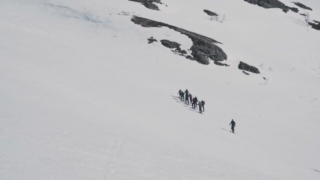 Group of hikers climbing up snowy mountain in Norway, Vatnahalsen region. Aerial view