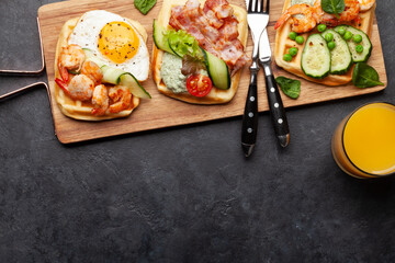 Breakfast waffles with fried eggs, salmon, cucumber and prawns