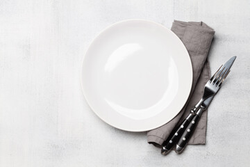 Empty plate and silverware on stone table