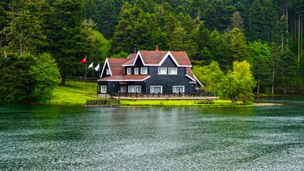 Impressive lake house. House on the shore of Cennet Gol (Paradise Lake), Bolu. Reflected on water. Country side, forest and farm field, lake with house. Traditional government building on lake coast. © Akin Ozcan