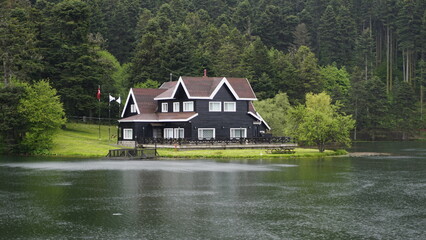 Impressive lake house. House by the lake on the shore of Cennet Gol (Paradise Lake), Bolu. Country side, forest and farm field, lake with house.