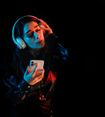 latin young woman with headphones listening to music over color neon and black background in Mexico Latin America