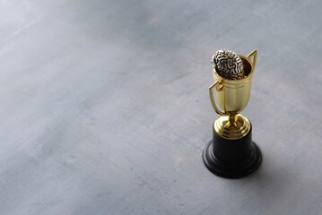 Brain inside gold cup trophy with copy space. Winning mentality and mindset concept. - obrazy, fototapety, plakaty