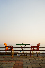Orange plastic chairs with furniture at the seaside terrace with sky on background