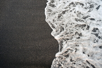 Dark sand and foamy wave background. Natural Seaside texture