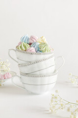 Colored airy meringues on a gray background in tea mugs. Vertical image, selective focus